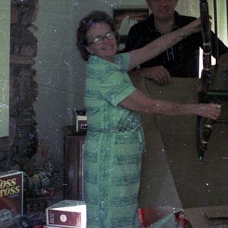 Three people posing with an old wooden rocking chair indoors.