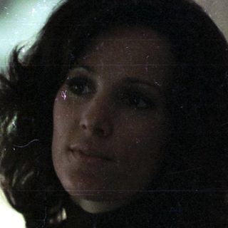 Woman in 1970s-style sweater by Christmas tree.