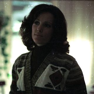 Woman in 1970s-style sweater by Christmas tree.