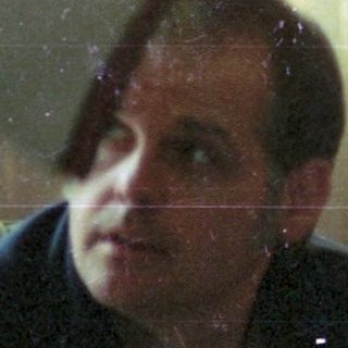 Man sitting indoors near Christmas tree.
