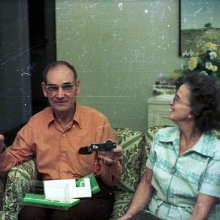 Two elderly people playing video game together indoors.