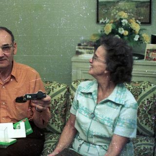 Two elderly people playing video game together indoors.