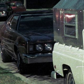 Vintage white Ford pickup truck with camper shell parked.
