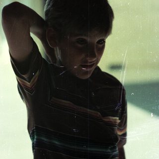 Boy touching hair near window with spiderweb.