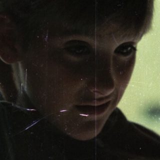 Boy touching hair near window with spiderweb.