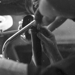 Person playing a saxophone through a foggy window.