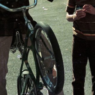 Two boys walking with bicycles outdoors.