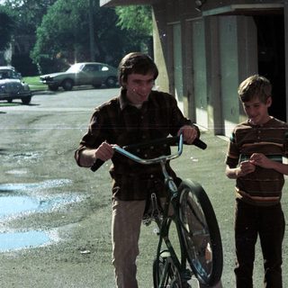Two boys walking with bicycles outdoors.