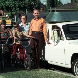 Family posing with bicycles and vintage van.