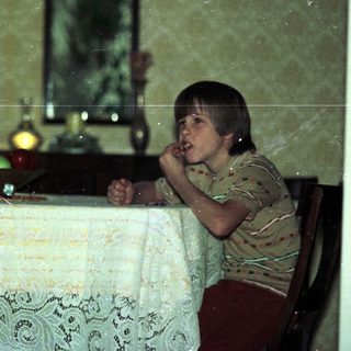 Child sitting at vintage table eating.