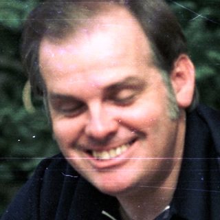 Smiling man in dark shirt near decorated Christmas tree.