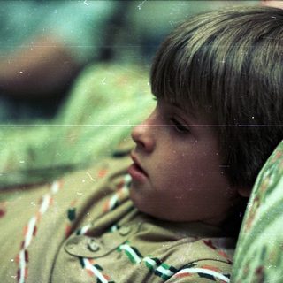Boy resting with head on camouflage jacket.