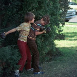 Two children carrying a large bundle of greenery.