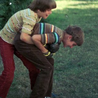 Two boys playing outdoors, one lifting the other.