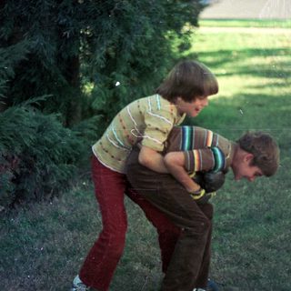 Two boys playing outdoors, one lifting the other.