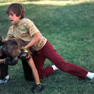 Two boys wrestling playfully outdoors.