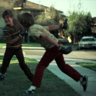 Two boys playing baseball near rental office.