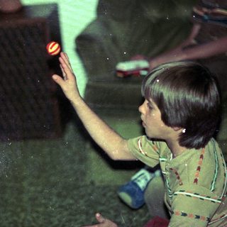 Child playing with glowing toy in dim room.