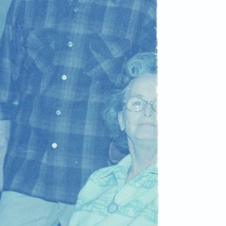 Young man in plaid shirt with elderly woman indoors.