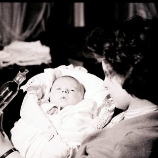 A woman baptizing an infant with holy water.