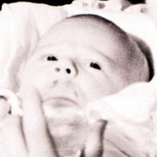 A woman cradles a newborn baby indoors.