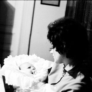 A woman cradles a newborn baby indoors.