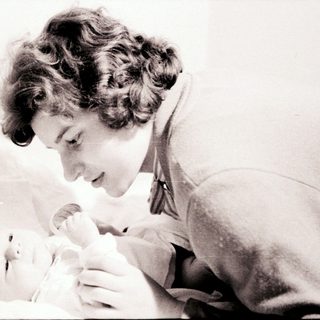 A woman tenderly holding a newborn baby.