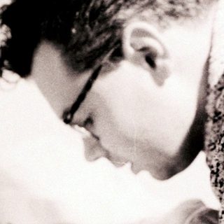 A man gently holds and examines a newborn baby.