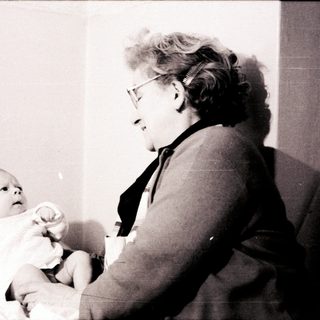 A woman holding a baby indoors.