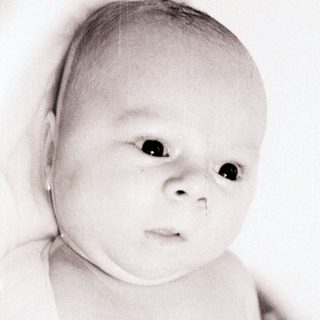 Tender moment of infant being held.
