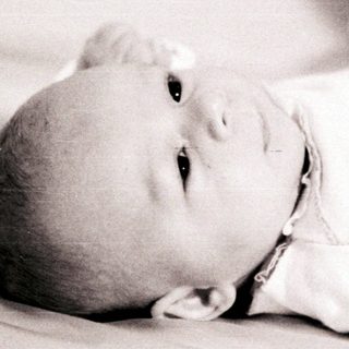 Infant lying peacefully on bed.