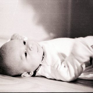 Infant lying peacefully on bed.
