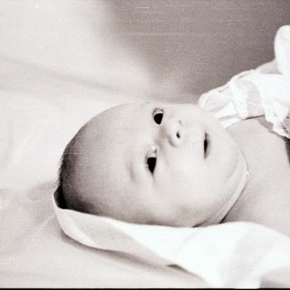 Newborn baby lying peacefully on soft blanket.