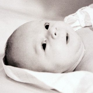 Newborn baby lying peacefully on soft blanket.