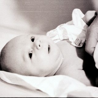 Newborn baby lying peacefully on soft blanket.