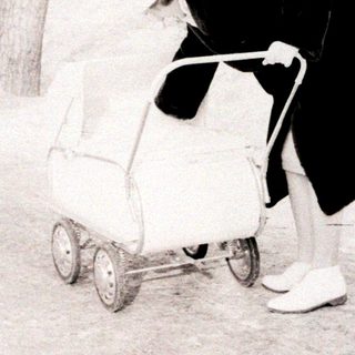 Person pushing stroller in snowy outdoor area.