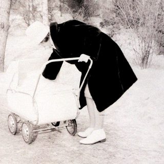 Person pushing stroller in snowy outdoor area.