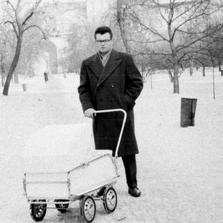 Man pushing cart in snowy park.