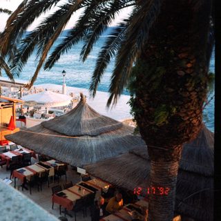 Tropical beachside restaurant with thatched umbrellas.
