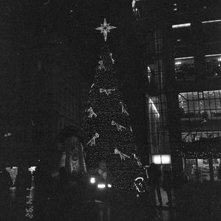 Illuminated Christmas tree in urban night setting.