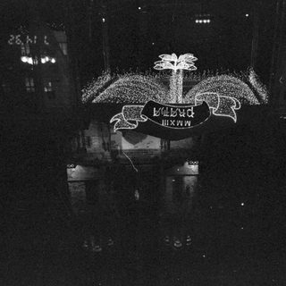 Illuminated banner reading "PMXXIII PRAHA" at night.