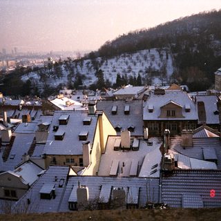 Snow-covered rooftops in urban hillside area.