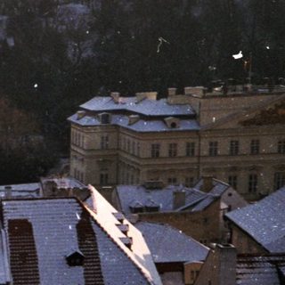 Snow-covered rooftops in urban hillside area.