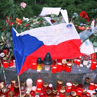 Memorial tribute with candles, flowers, and Czech flag.