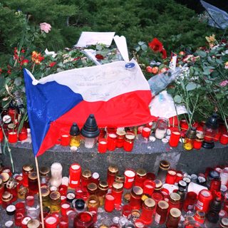 Memorial tribute with candles, flowers, and Czech flag.