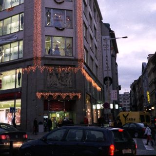 Urban street scene with illuminated storefronts and evening traffic.