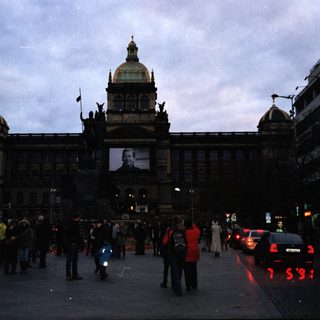 Historic building facade with crowd and evening traffic.