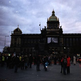 Historic building facade with crowd and evening traffic.