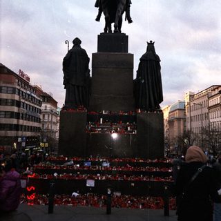 Statue with memorial candles and figures.