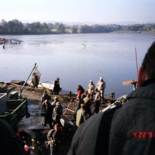 People fishing and working on a lake shore.